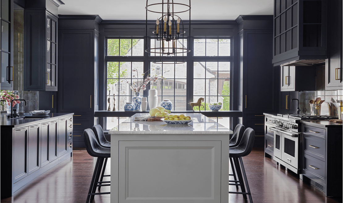 A wide shot of Karen Ferguson's design that emphasizes the open lighting and deep navy-hued colors of the kitchen.