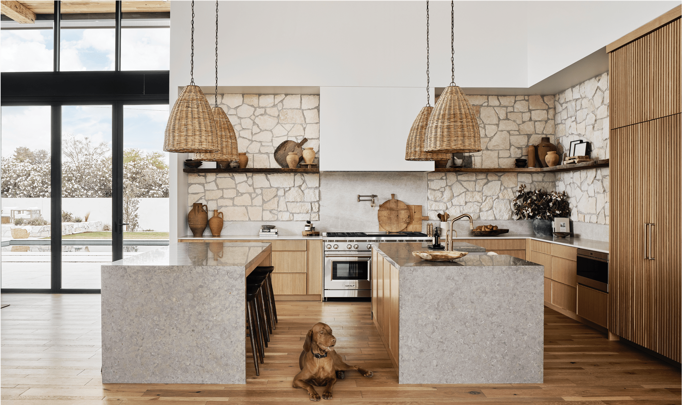 The kitchen features Woven Tulum pendant lights from Modern Nest hang above dual kitchen islands.