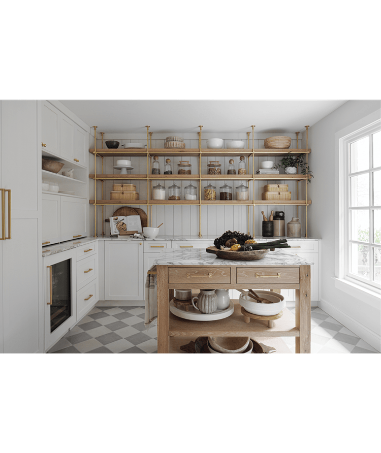 A white marble-colored kitchen featuring a wood-colored table with an assortment of fruits and vegetables on top.