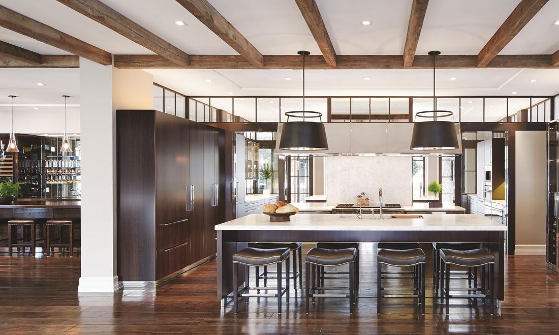 Luxury kitchen design offering warmth and comfort with wood paneling and wooden cabinetry featuring a seamless and hidden panel ready Sub Zero refrigerator.