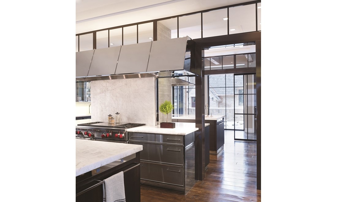 Luxury kitchen design offering warmth and comfort with wood paneling and wooden cabinetry featuring a seamless and hidden panel ready Sub Zero refrigerator.