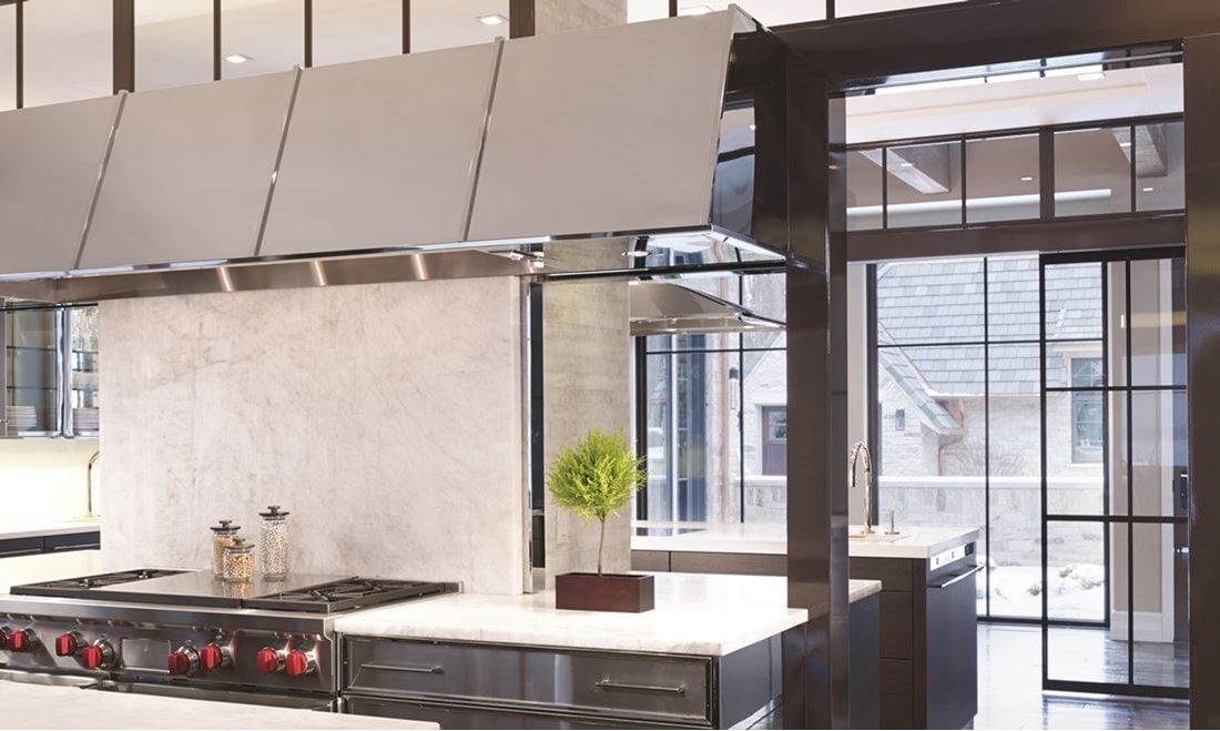 Luxury kitchen design offering warmth and comfort with wood paneling and wooden cabinetry featuring a seamless and hidden panel ready Sub Zero refrigerator.