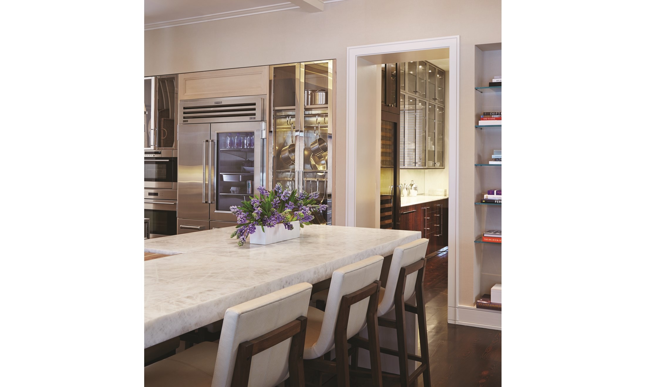 Luxury kitchen design offering warmth and comfort with wood paneling and wooden cabinetry featuring a seamless and hidden panel ready Sub Zero refrigerator.