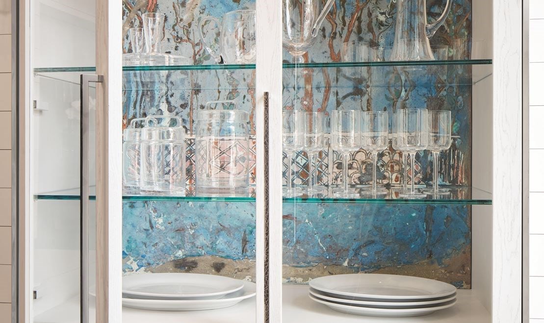 A custom-fired terracotta mural in ethereal blues, handmade in Italy, backs the interior of a de Giulio designed china cabinet.