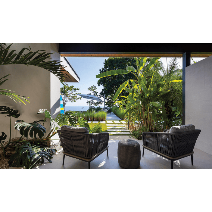 Two chairs underneath a canopy looking out into the outside area of the luxury home.