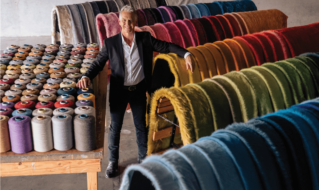 Kyle Bunting posing with the one-hundred-and-twenty-five colors of hides that he offers and designs.