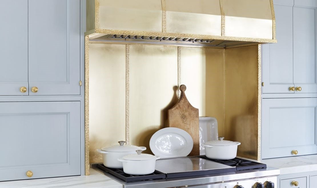 The hood above the Wolf range is crafted from peened brass.