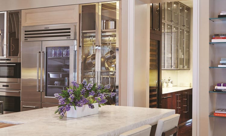 Luxury kitchen design offering warmth and comfort with wood paneling and wooden cabinetry featuring a seamless and hidden panel ready Sub Zero refrigerator.