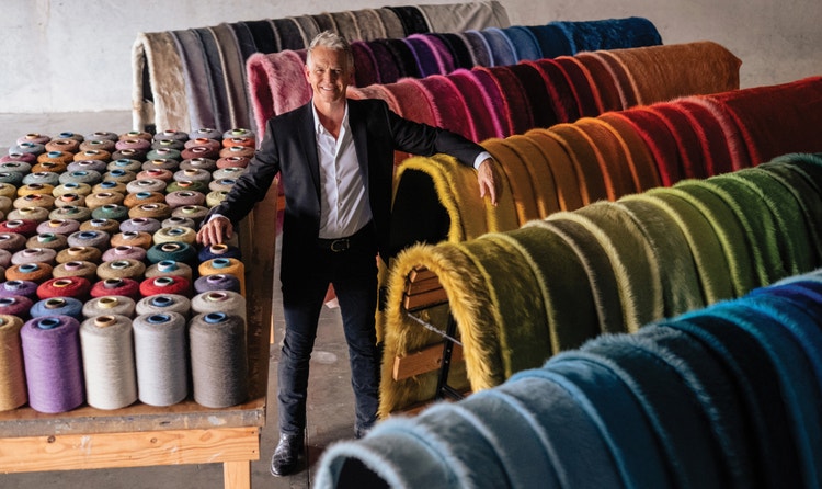 Kyle Bunting posing with the one-hundred-and-twenty-five colors of hides that he offers and designs.