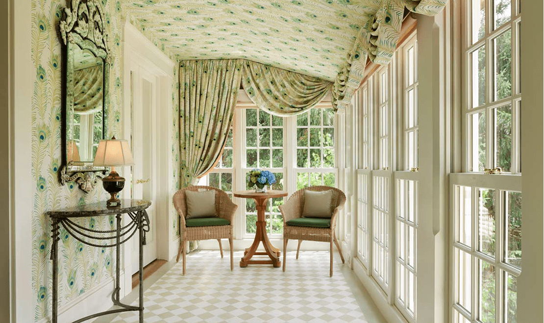 A beautiful green-colored hallway with two chairs at the end and windows covering the entire outside area.