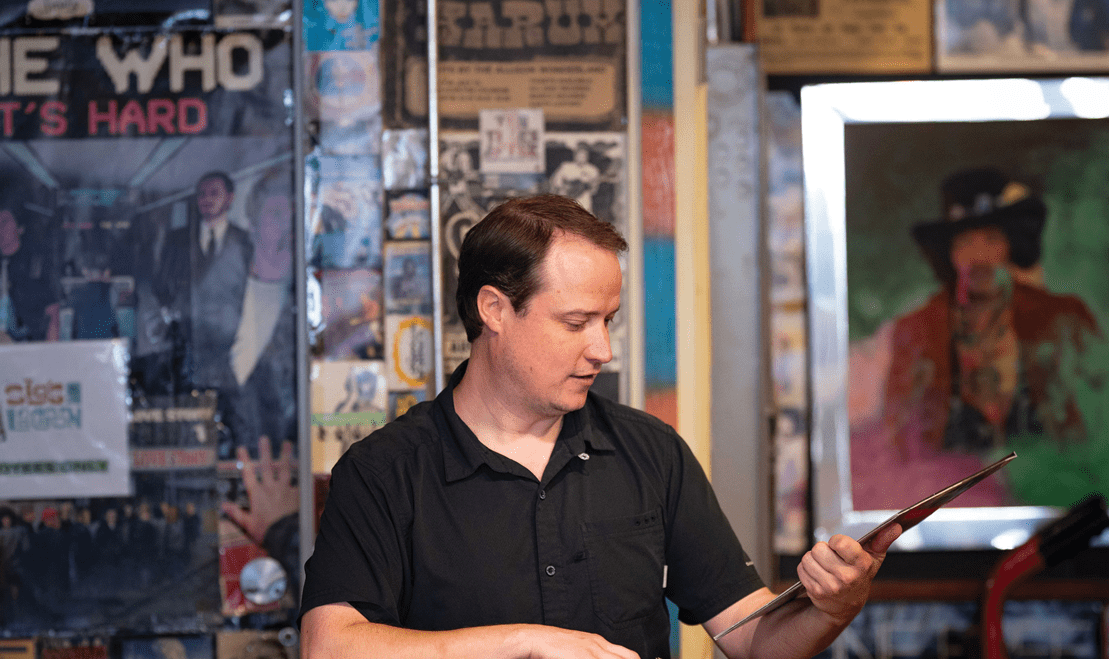 Professional Chef, Colin Shine, holding a vintage vinyl record in his hands while at a record store.