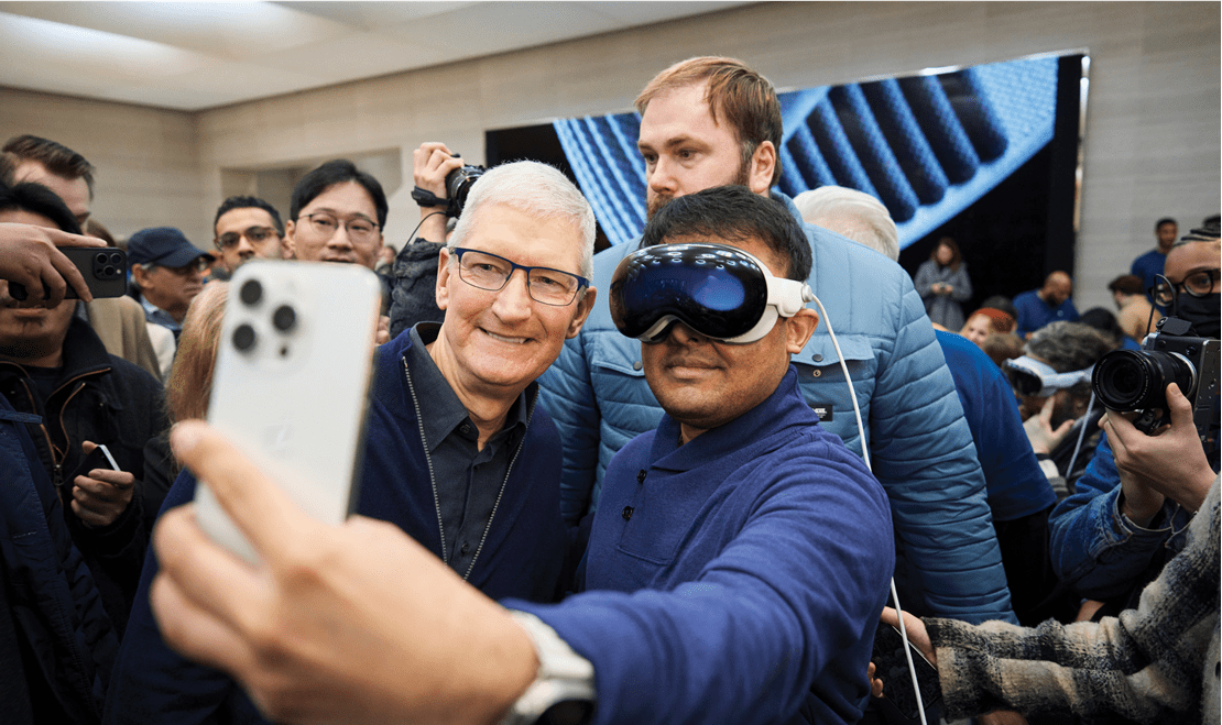 A customer wearing an Apple Vision Pro poses with Apple's CEO Tim Cook for a selfie.