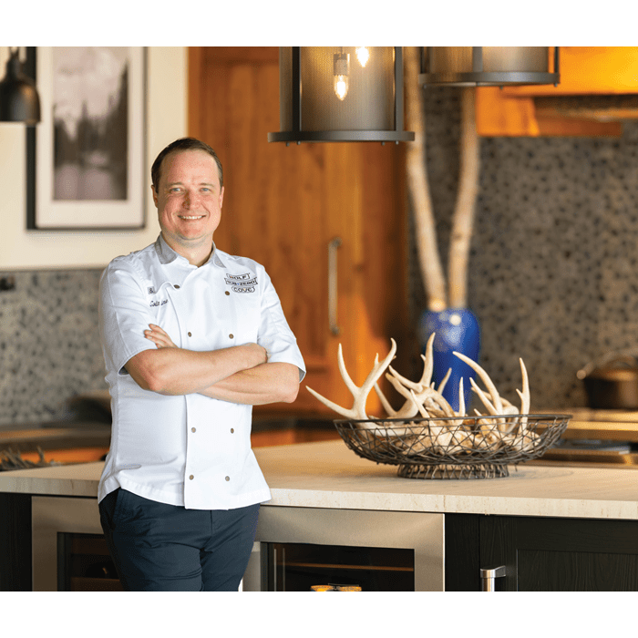 Sub-Zero, Wolf, and Cove Corporate Chef, Colin Shine, posing and smiling in front of a beautiful kitchen.