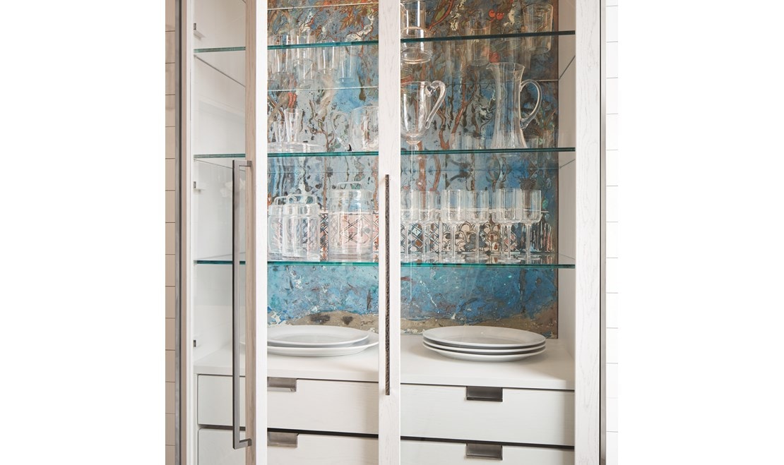 A custom-fired terracotta mural in ethereal blues, handmade in Italy, backs the interior of a de Giulio designed china cabinet.