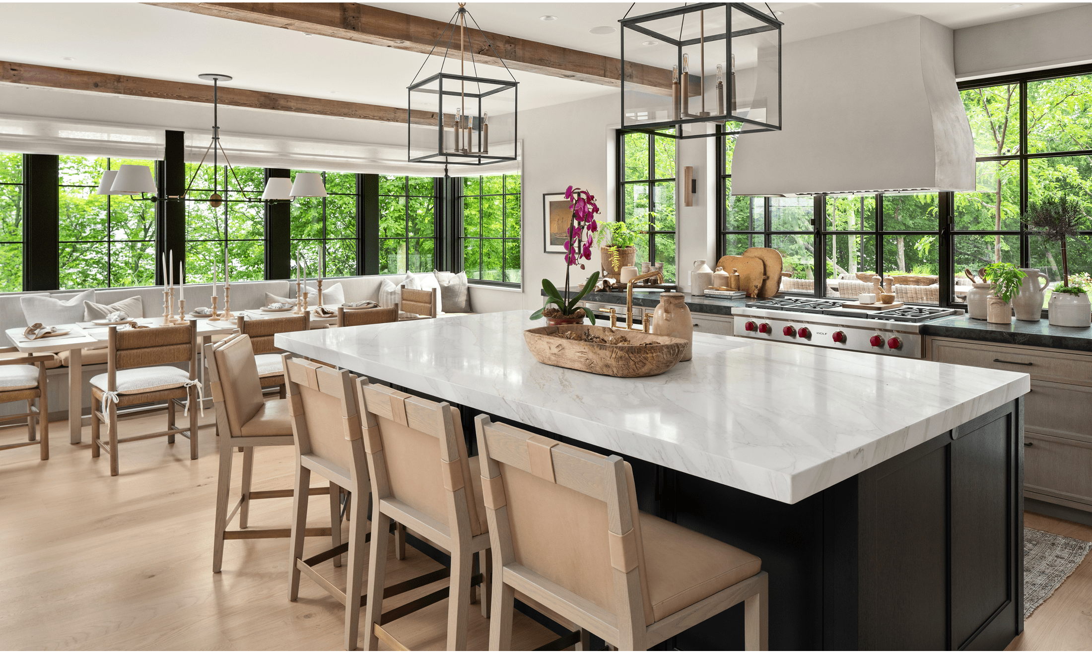 The kitchen features a large island table, a long dining room table, and the mainstay of the area, a Wolf 48" Gas Range.