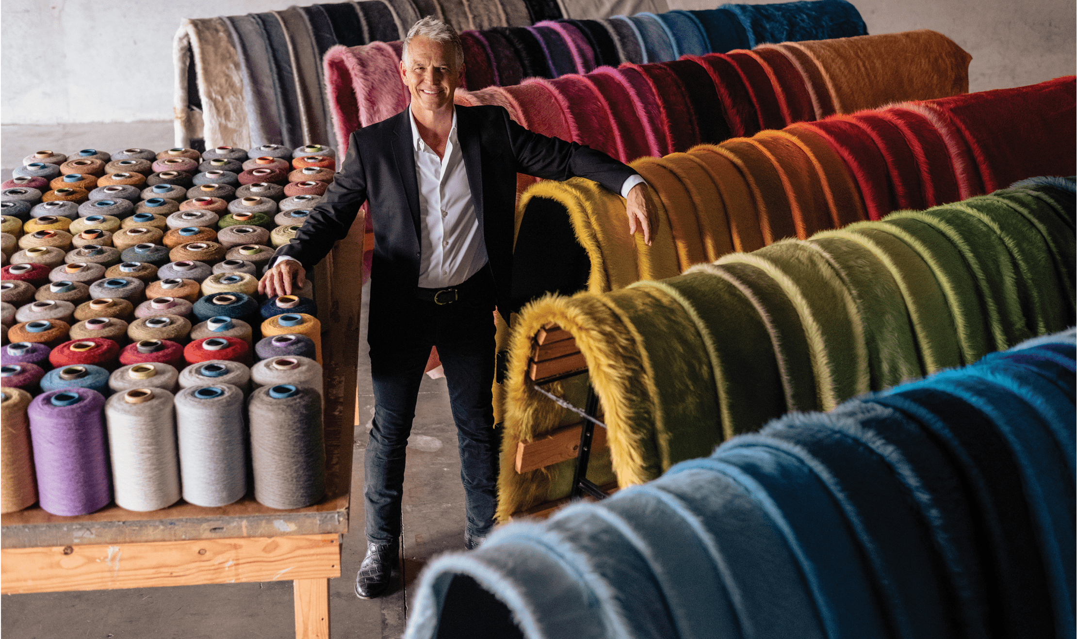 Kyle Bunting posing with the one-hundred-and-twenty-five colors of hides that he offers and designs.