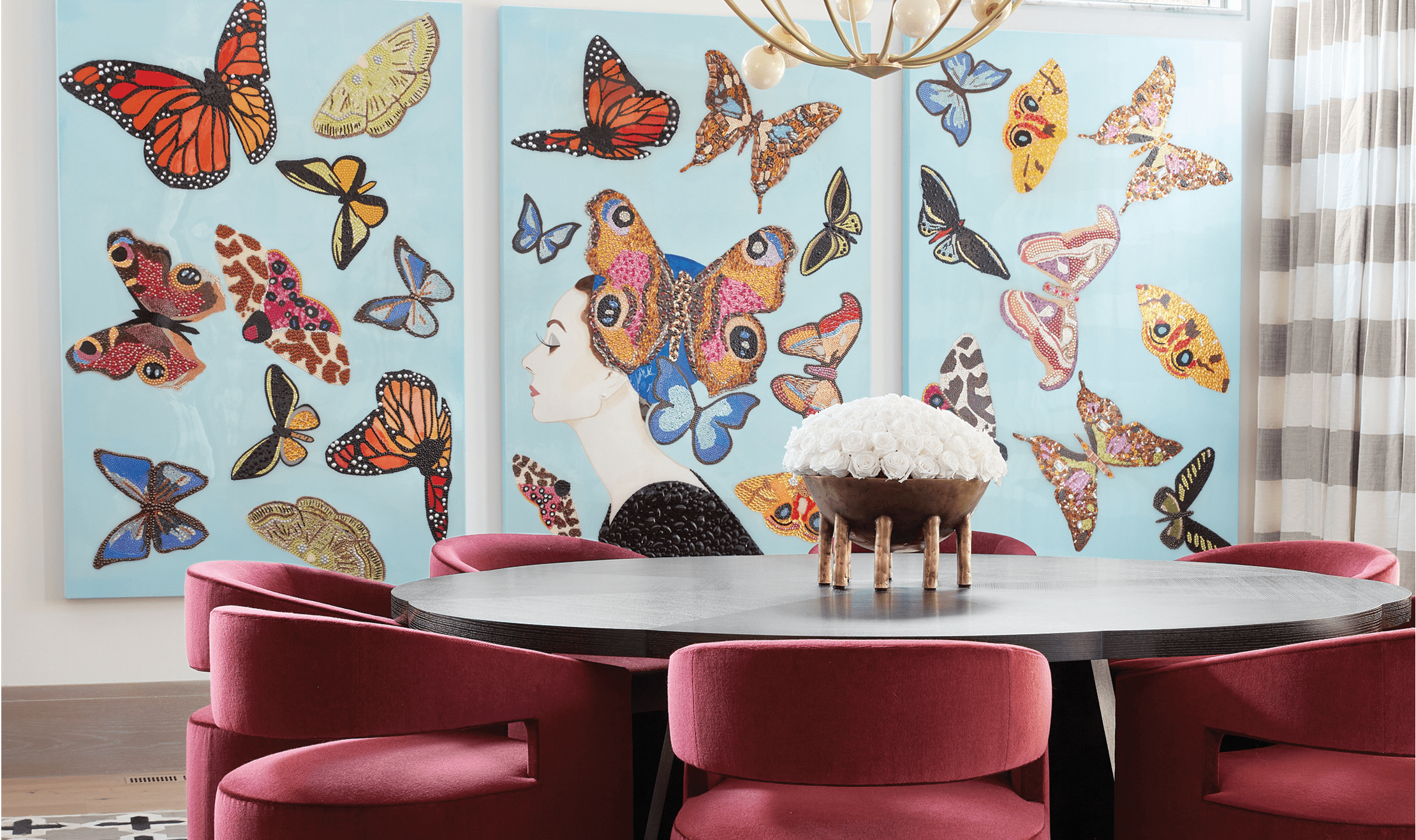 A colorful butterfly wall behind a white table and red chairs designed by Kris Lajeskie and Jennifer Welch.