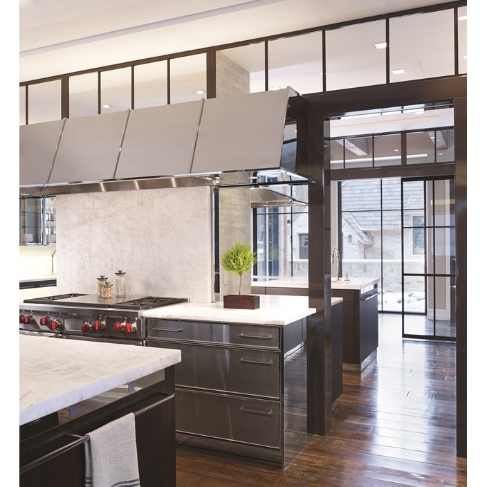 Luxury kitchen design offering warmth and comfort with wood paneling and wooden cabinetry featuring a seamless and hidden panel ready Sub Zero refrigerator.