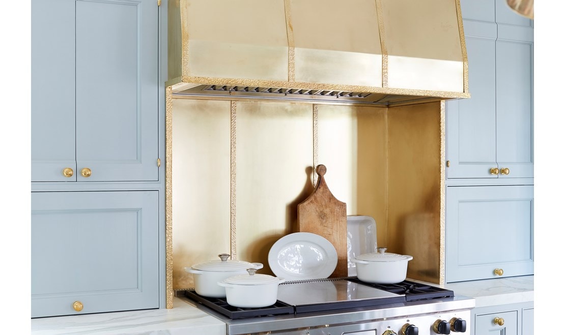 The hood above the Wolf range is crafted from peened brass.