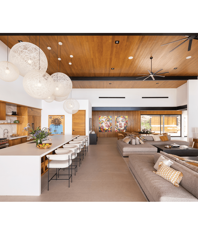 A contemporary, luxury open kitchen and living room design with beautiful artworks and a Wolf Appliances Range.