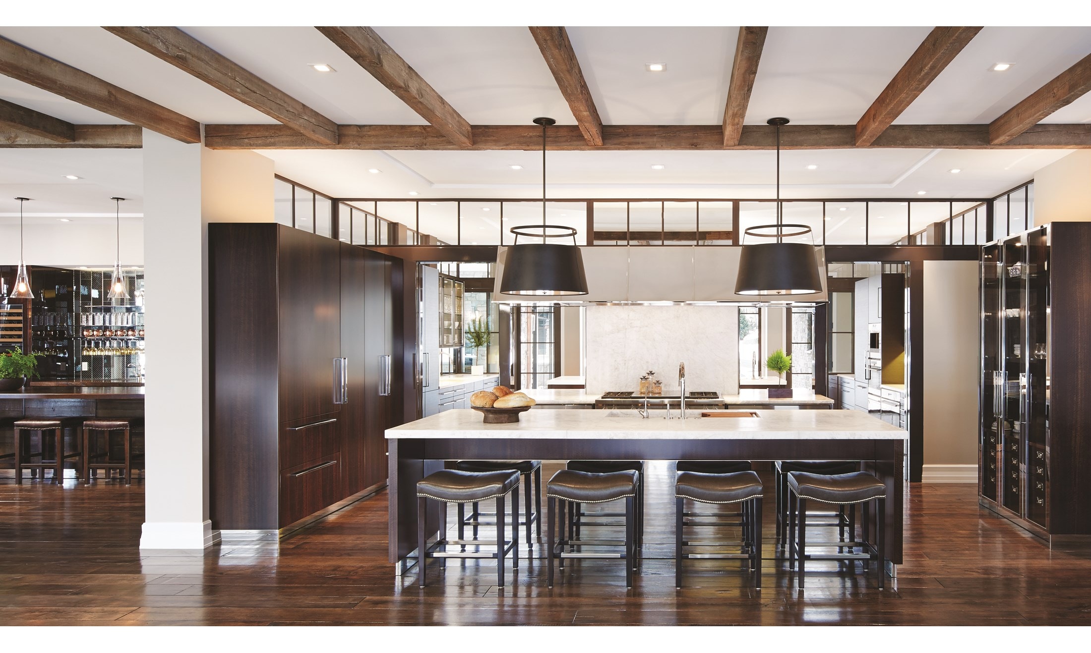 Luxury kitchen design offering warmth and comfort with wood paneling and wooden cabinetry featuring a seamless and hidden panel ready Sub Zero refrigerator.