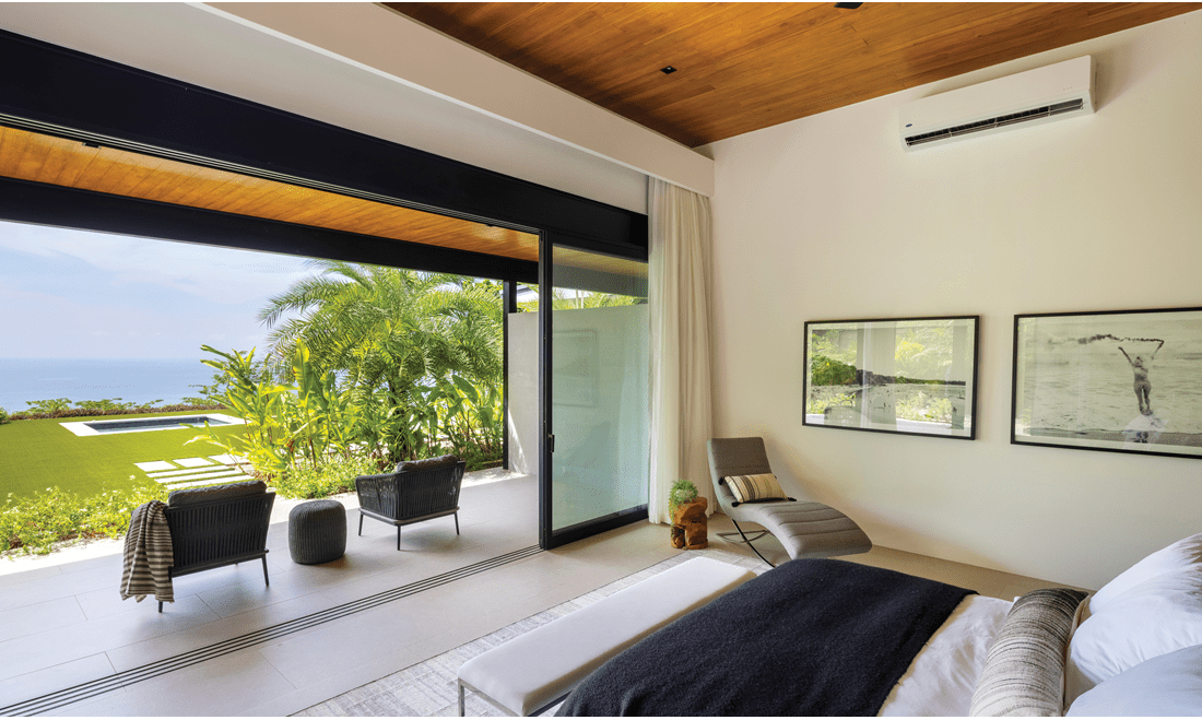 The suite has a spacious bed, closable glass doors to the outside patio area, and unique artwork on the walls.