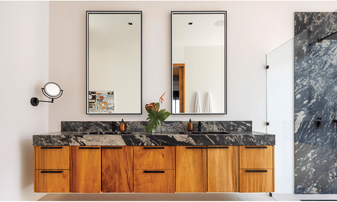The bathroom has double mirrors and two sinks, along with a beautiful marble countertop that matches the shower wall.