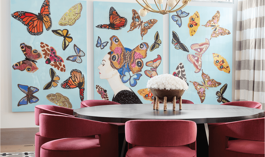 A colorful butterfly wall behind a white table and red chairs designed by Kris Lajeskie and Jennifer Welch.
