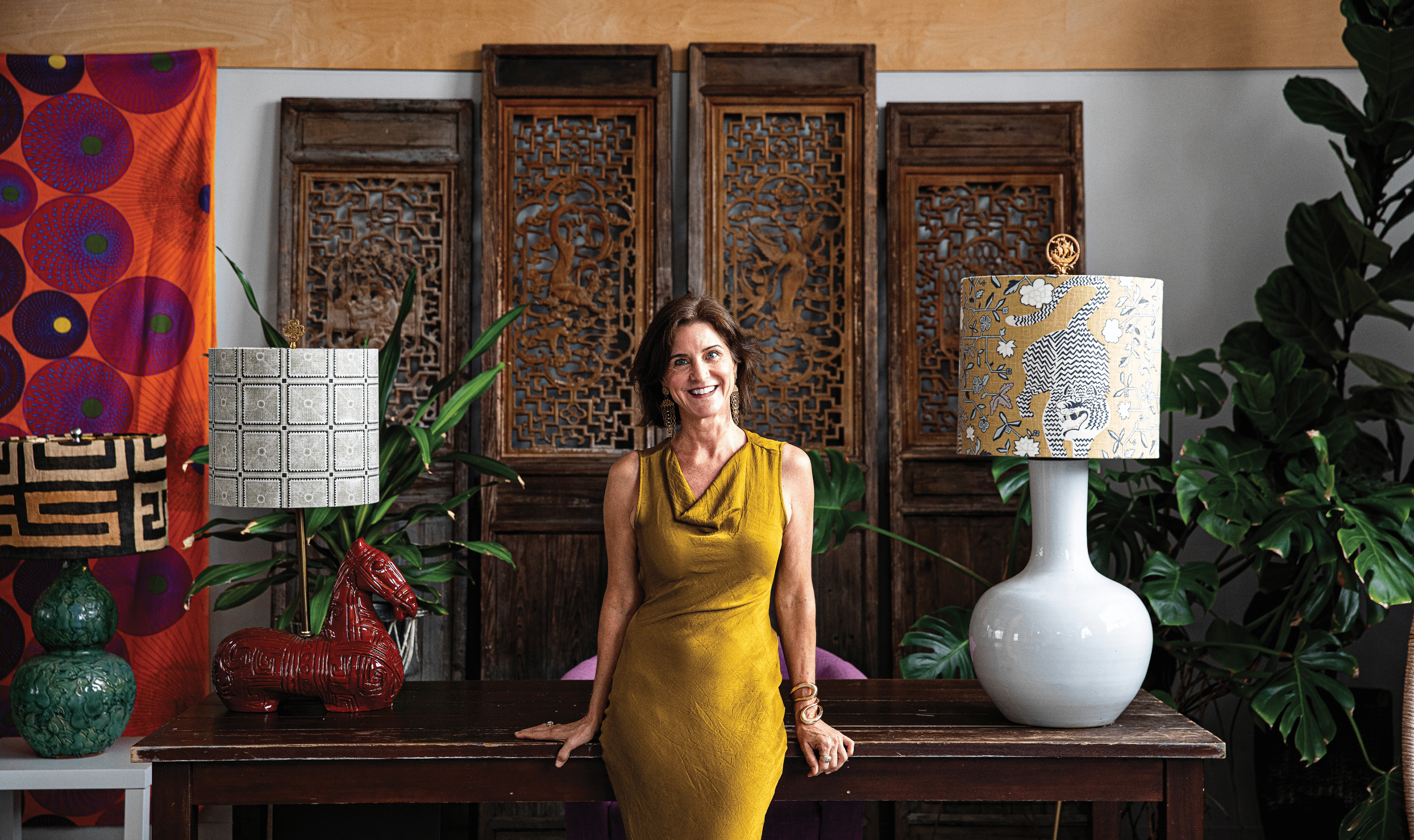 Helen Rutledge, founder of Bibelot Home, posing next to multiple lampshades designed and created by her team.