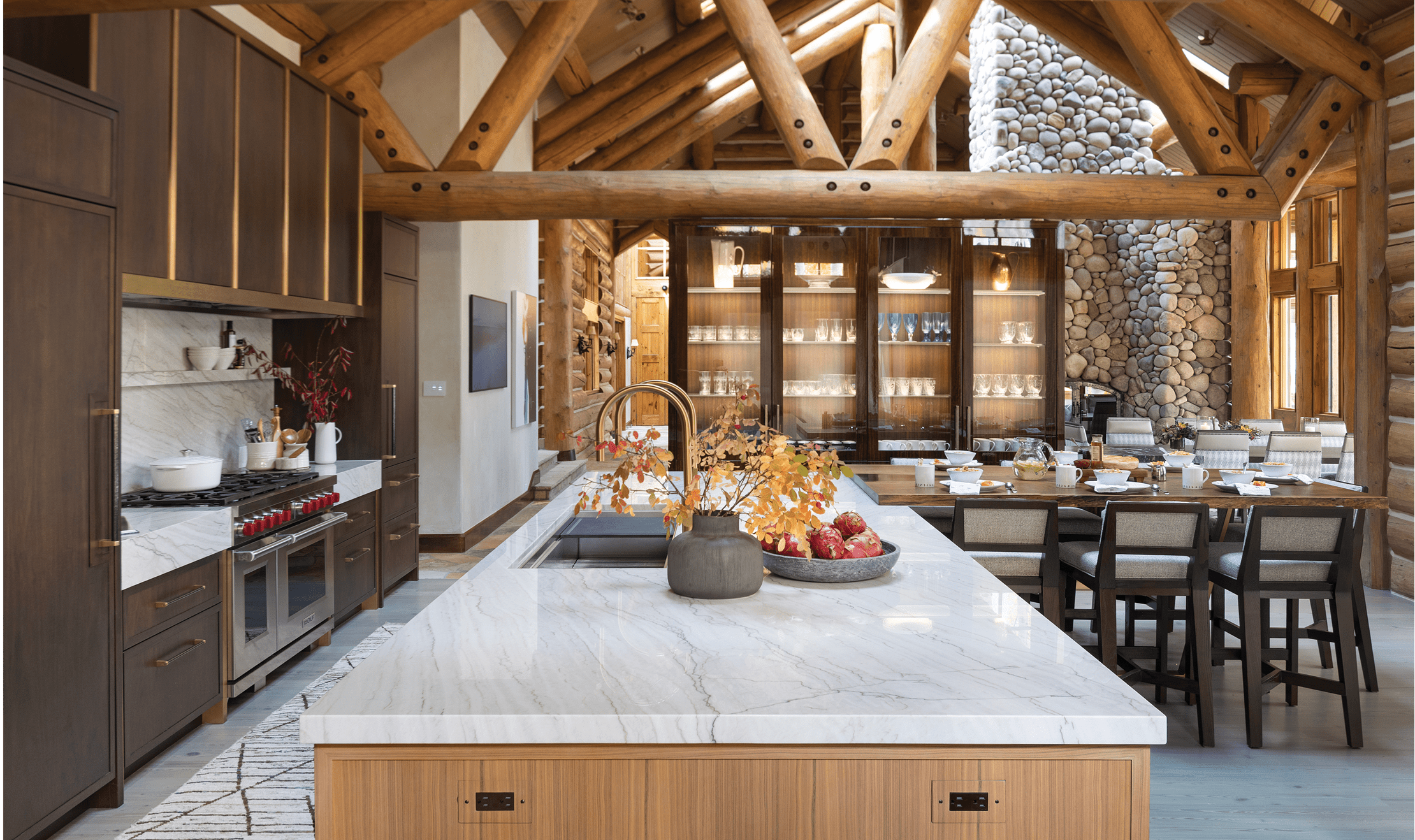 Transparent glass doors highlight an illuminated display and a light grey quartzite countertop outlines the kitchen island.