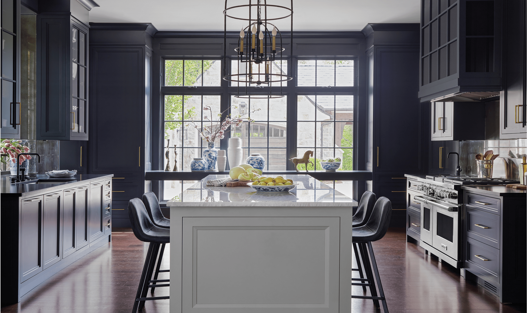 A wide shot of Karen Ferguson's design that emphasizes the open lighting and deep navy-hued colors of the kitchen.