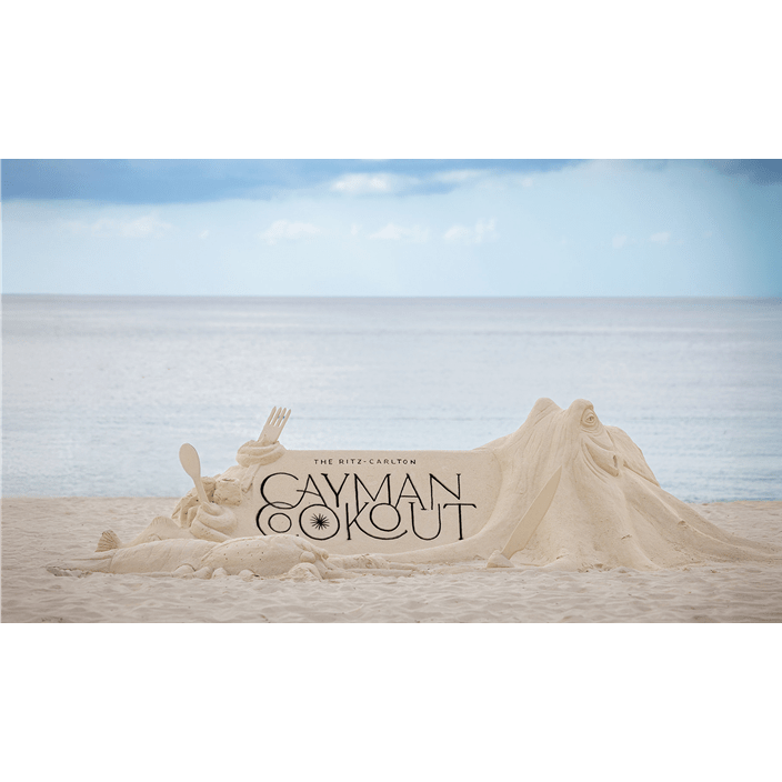 A sand sculpture with "The Ritz-Carlton Cayman Cookout" written on top of it in black.