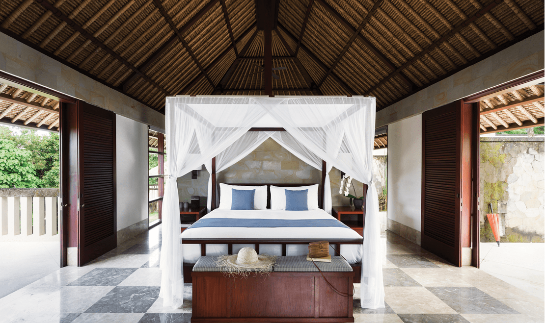 A garden suite at REVĪVŌ Wellness Resort in Bali, Indonesia featuring canopy curtains hanging over the bed.