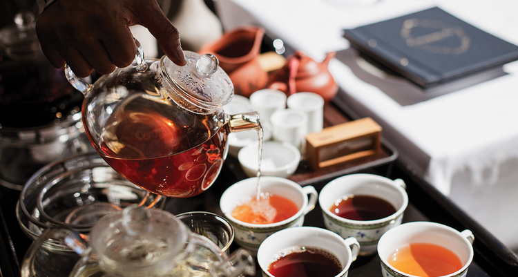 A worker pouring a cup of Mount Nelson's signature tea next to three other cups of different tea options.